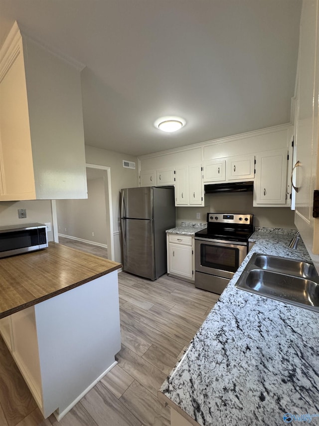 kitchen with sink, stainless steel appliances, white cabinets, and light wood-type flooring