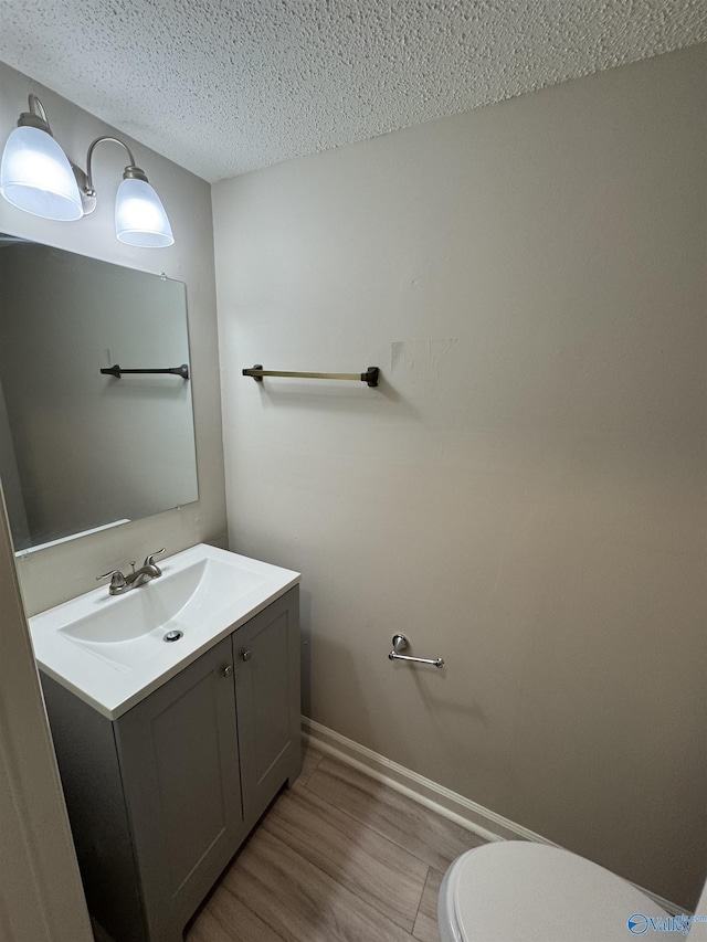 bathroom featuring hardwood / wood-style floors, a textured ceiling, vanity, and toilet