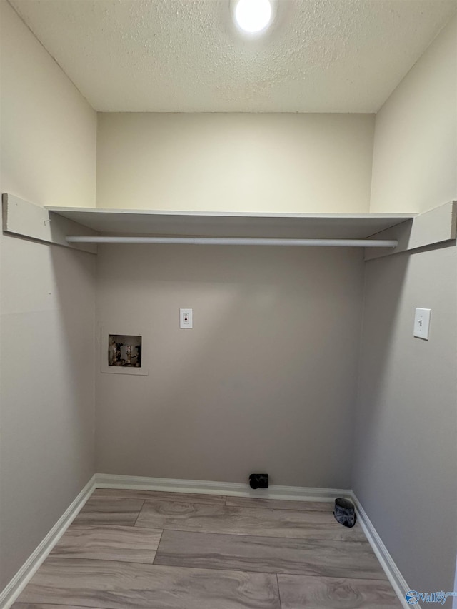 laundry room featuring washer hookup, light wood-type flooring, and a textured ceiling