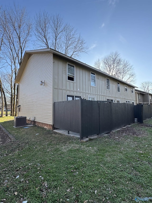 view of side of home featuring a lawn and central AC