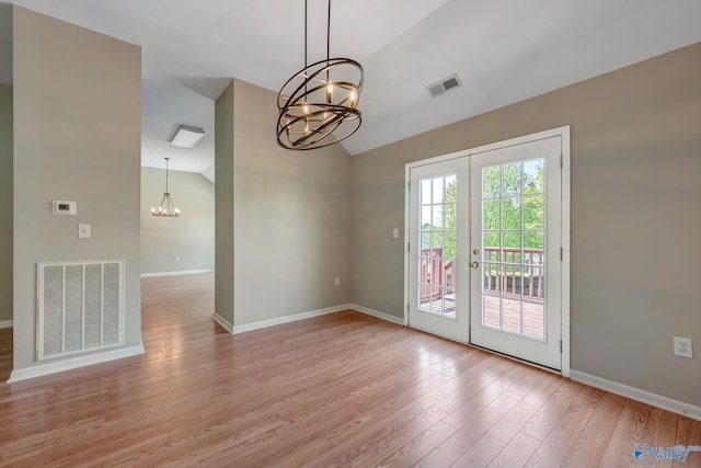 interior space featuring a notable chandelier, vaulted ceiling, french doors, light wood-style flooring, and visible vents