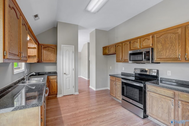 kitchen with light wood-style flooring, vaulted ceiling, a sink, and appliances with stainless steel finishes