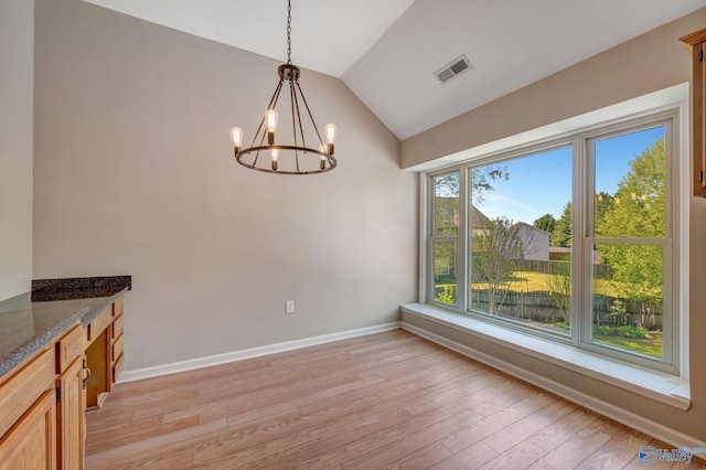 unfurnished dining area featuring visible vents, a chandelier, lofted ceiling, light wood finished floors, and baseboards