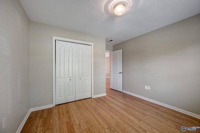 unfurnished bedroom with a closet, baseboards, and light wood finished floors