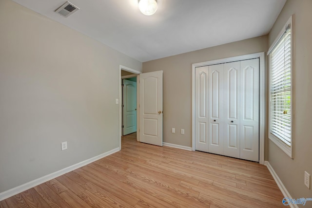 unfurnished bedroom with light wood-style flooring, baseboards, multiple windows, and visible vents