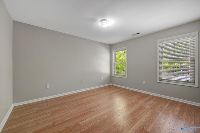 unfurnished room with visible vents, light wood-style flooring, and baseboards