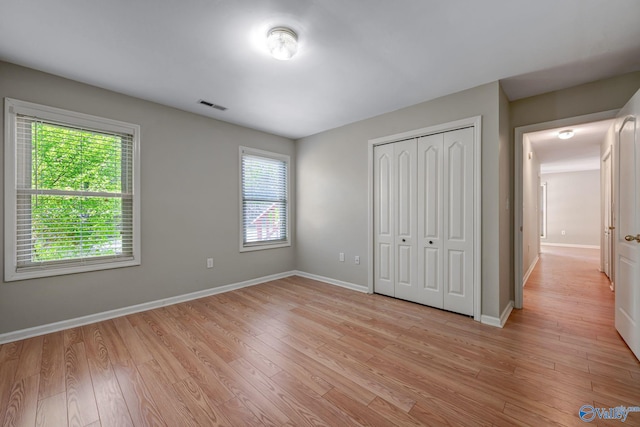 unfurnished bedroom featuring a closet, visible vents, baseboards, and light wood-style flooring
