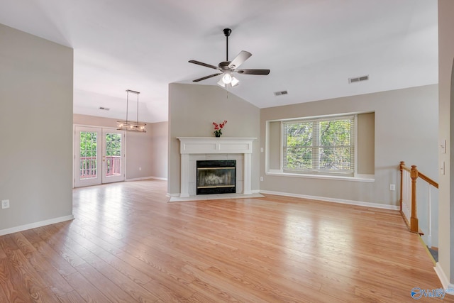 unfurnished living room with plenty of natural light, visible vents, ceiling fan with notable chandelier, and lofted ceiling