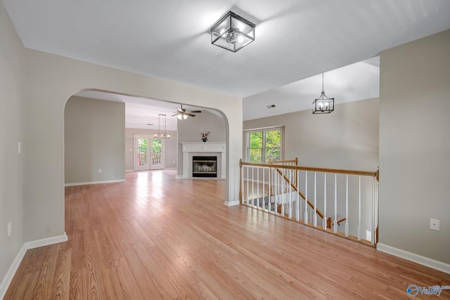 unfurnished living room featuring light wood finished floors, baseboards, and a healthy amount of sunlight