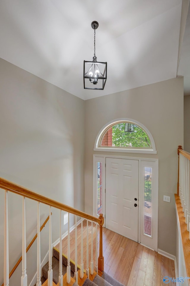 foyer entrance with baseboards, hardwood / wood-style floors, a chandelier, and stairs