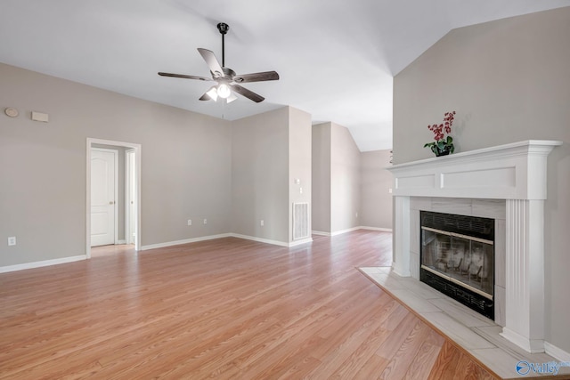 unfurnished living room with light wood-style floors, ceiling fan, a tiled fireplace, and baseboards