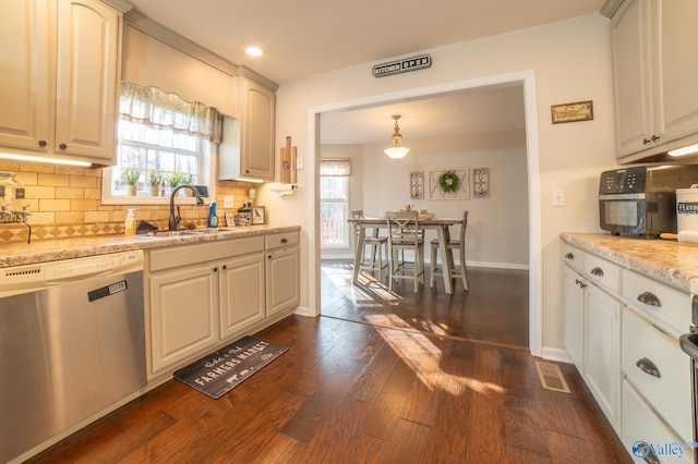 kitchen featuring light stone countertops, stainless steel dishwasher, sink, decorative light fixtures, and dark hardwood / wood-style floors