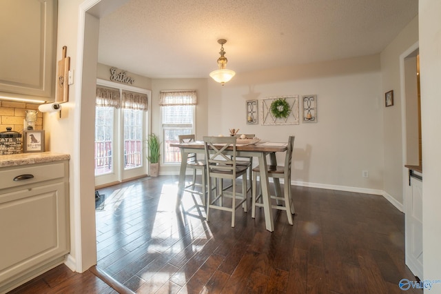 dining space with a textured ceiling and dark hardwood / wood-style flooring