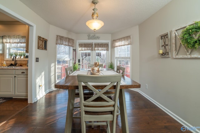 dining room with sink, dark hardwood / wood-style floors, and a textured ceiling