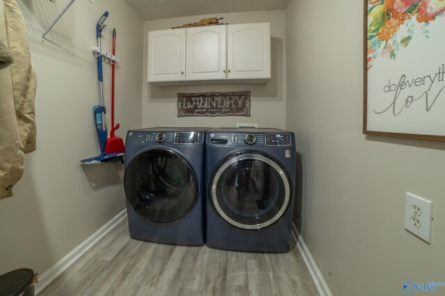 laundry room featuring cabinets, independent washer and dryer, a textured ceiling, and light hardwood / wood-style floors