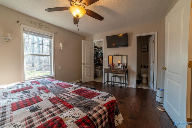 bedroom featuring ceiling fan, dark hardwood / wood-style flooring, ensuite bathroom, a walk in closet, and a closet