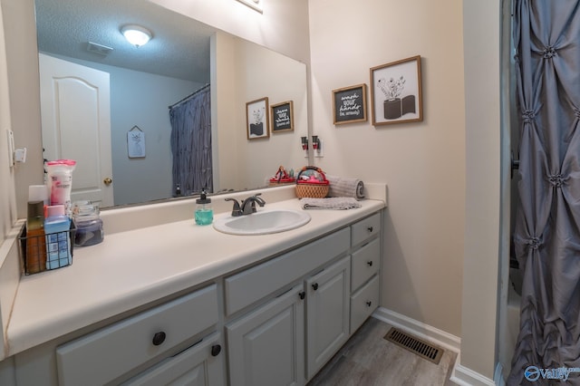 bathroom featuring hardwood / wood-style floors, vanity, a textured ceiling, and a shower with shower curtain