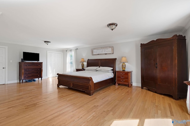 bedroom with baseboards, crown molding, light wood finished floors, and a closet