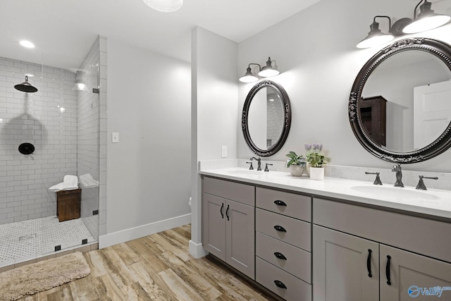 full bath featuring wood finished floors, a sink, and a tile shower