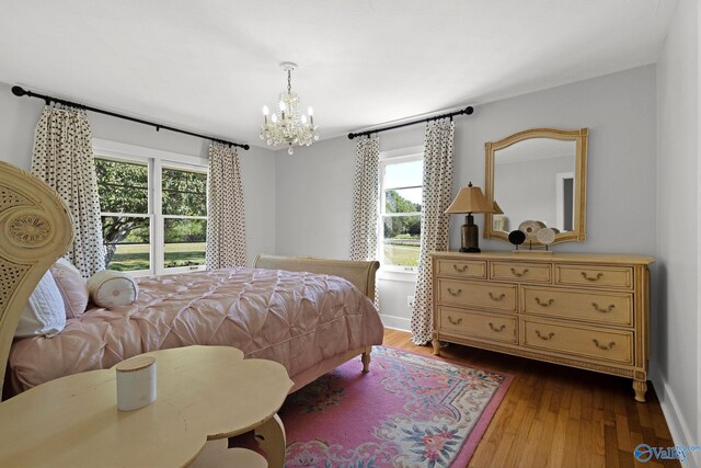 bedroom featuring dark wood-style flooring, baseboards, multiple windows, and an inviting chandelier
