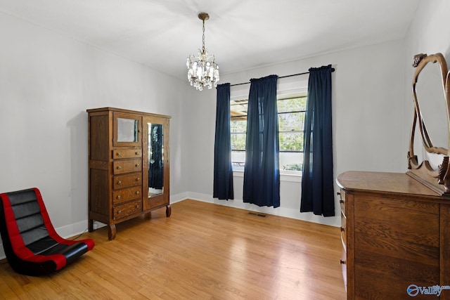 living area with light wood-style flooring, visible vents, baseboards, and a notable chandelier