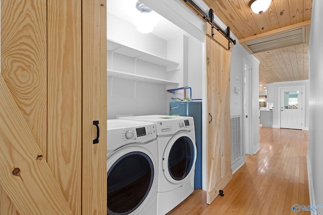 washroom featuring a barn door, laundry area, washing machine and clothes dryer, wood ceiling, and light wood-style flooring