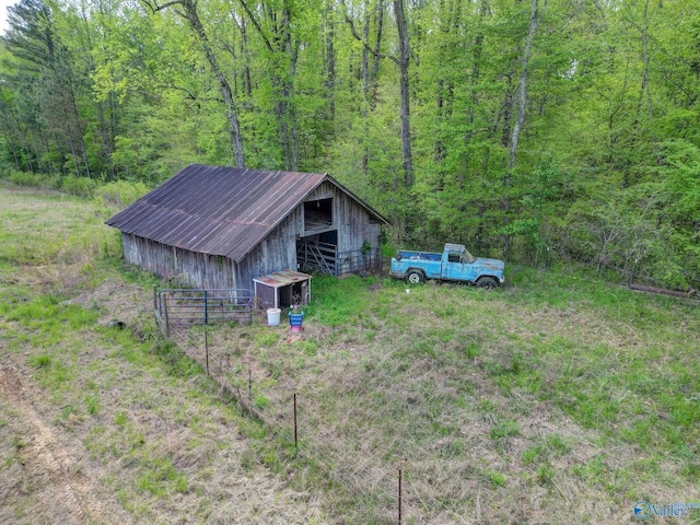 view of yard featuring an outdoor structure, a wooded view, and a pole building