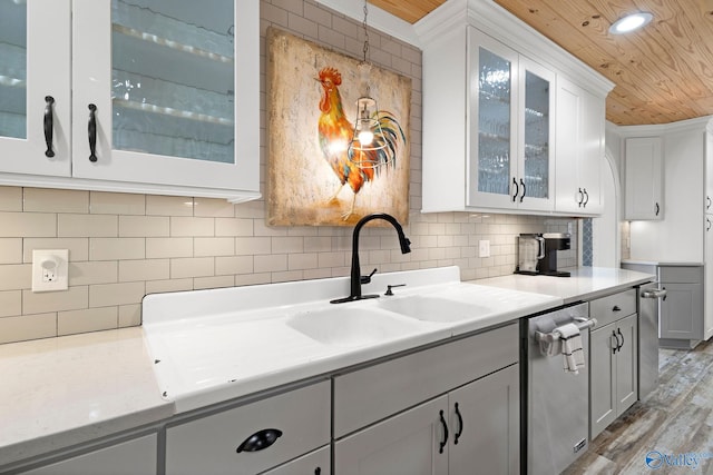 kitchen featuring decorative backsplash, light wood-style floors, glass insert cabinets, light countertops, and wooden ceiling