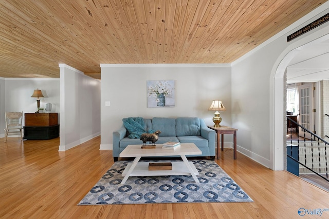 living room with wood finished floors, baseboards, arched walkways, and ornamental molding