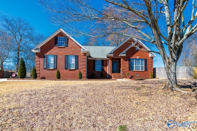 view of front of house featuring brick siding, crawl space, and fence