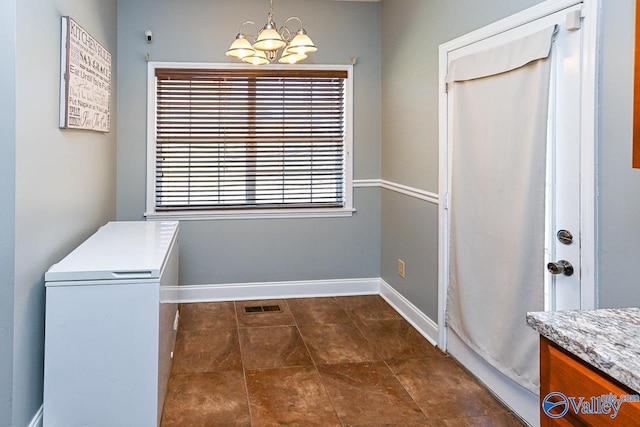 laundry room with an inviting chandelier, baseboards, and visible vents