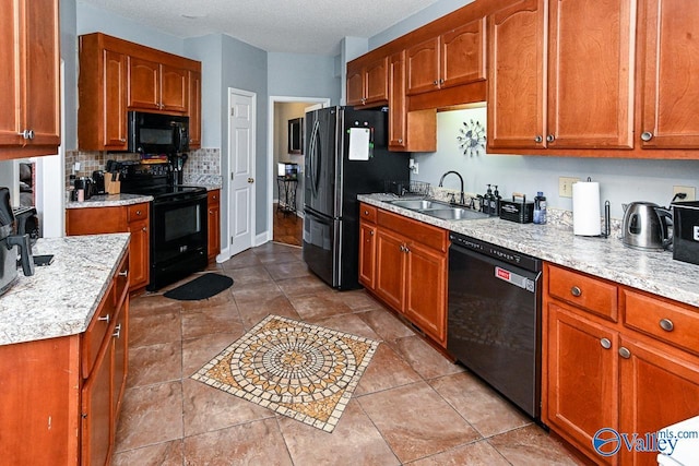 kitchen featuring a textured ceiling, a sink, light stone countertops, black appliances, and tasteful backsplash