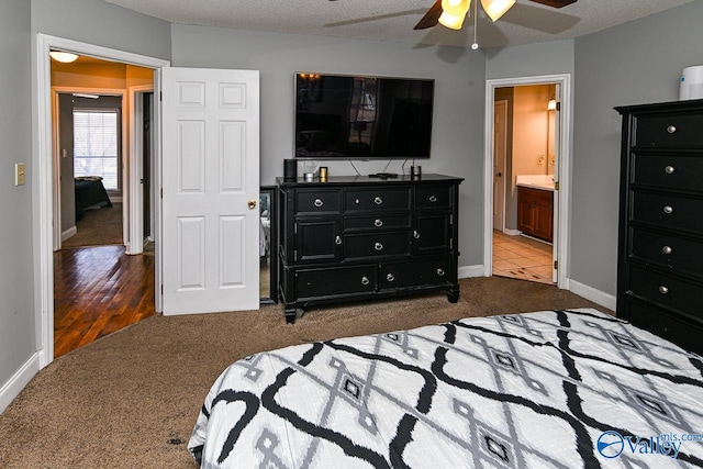 carpeted bedroom featuring ceiling fan, a textured ceiling, baseboards, and ensuite bath