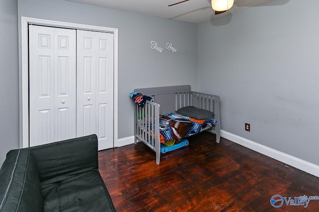 bedroom featuring dark wood-type flooring, a closet, a ceiling fan, and baseboards