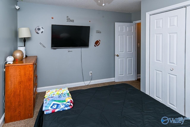 bedroom with a textured ceiling, dark colored carpet, a closet, and baseboards