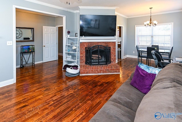 living area featuring a notable chandelier, dark wood-style flooring, a fireplace, baseboards, and crown molding