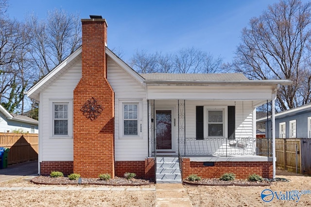 bungalow-style house with a shingled roof, a chimney, crawl space, covered porch, and fence