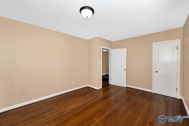 unfurnished bedroom with dark wood-type flooring and baseboards