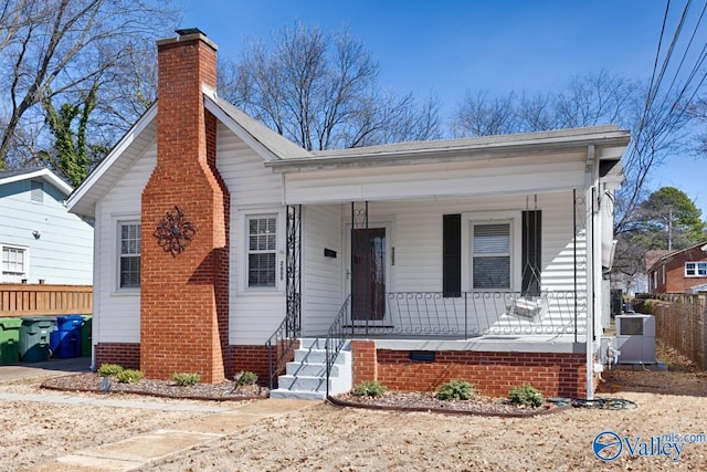 bungalow with covered porch, central AC, a chimney, and fence