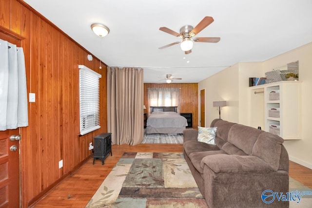 living room with wood walls, light wood-type flooring, and a ceiling fan