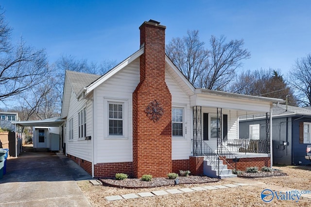 view of property exterior with a carport, covered porch, driveway, and a chimney