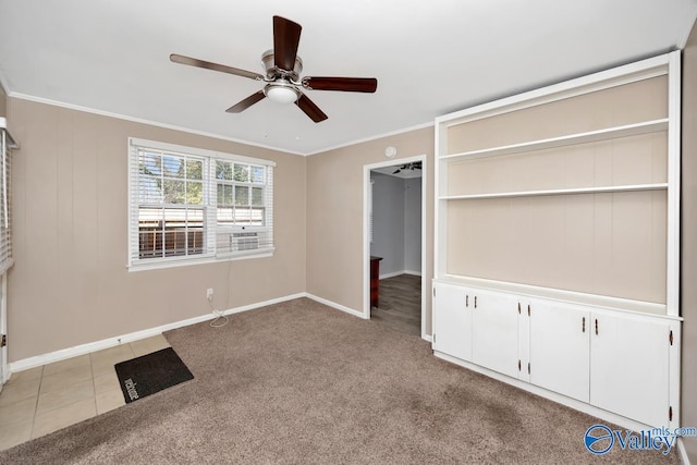 unfurnished bedroom with light carpet, baseboards, a ceiling fan, crown molding, and light tile patterned flooring