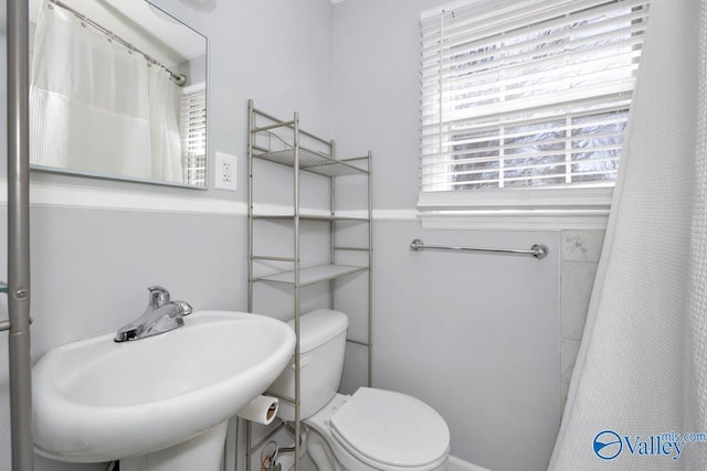 bathroom featuring curtained shower, a sink, and toilet