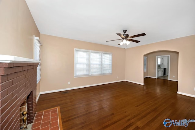 unfurnished living room featuring ceiling fan, a fireplace, wood finished floors, and baseboards