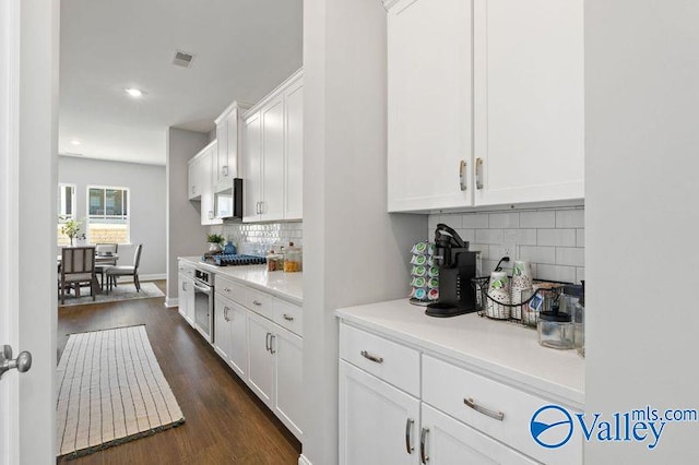 kitchen featuring dark wood finished floors, tasteful backsplash, white cabinetry, visible vents, and light countertops
