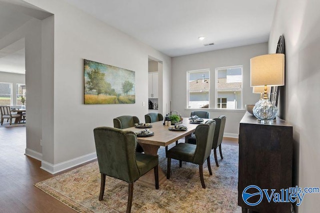 dining room with wood finished floors, baseboards, visible vents, and a wealth of natural light
