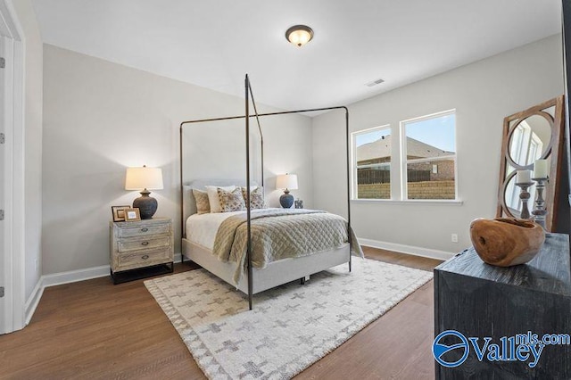 bedroom featuring wood finished floors, baseboards, and visible vents