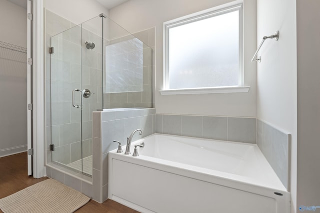 bathroom with a shower stall, a garden tub, and wood finished floors
