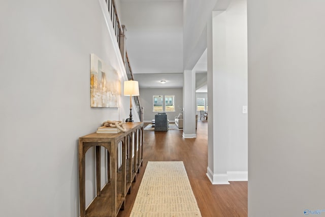 corridor with a high ceiling, baseboards, and wood finished floors