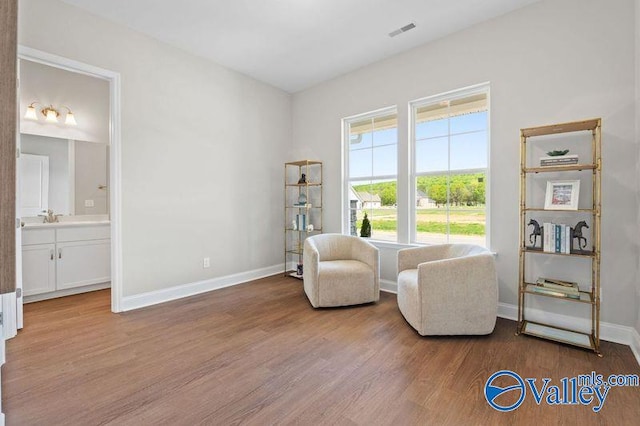 sitting room with wood finished floors, baseboards, and visible vents